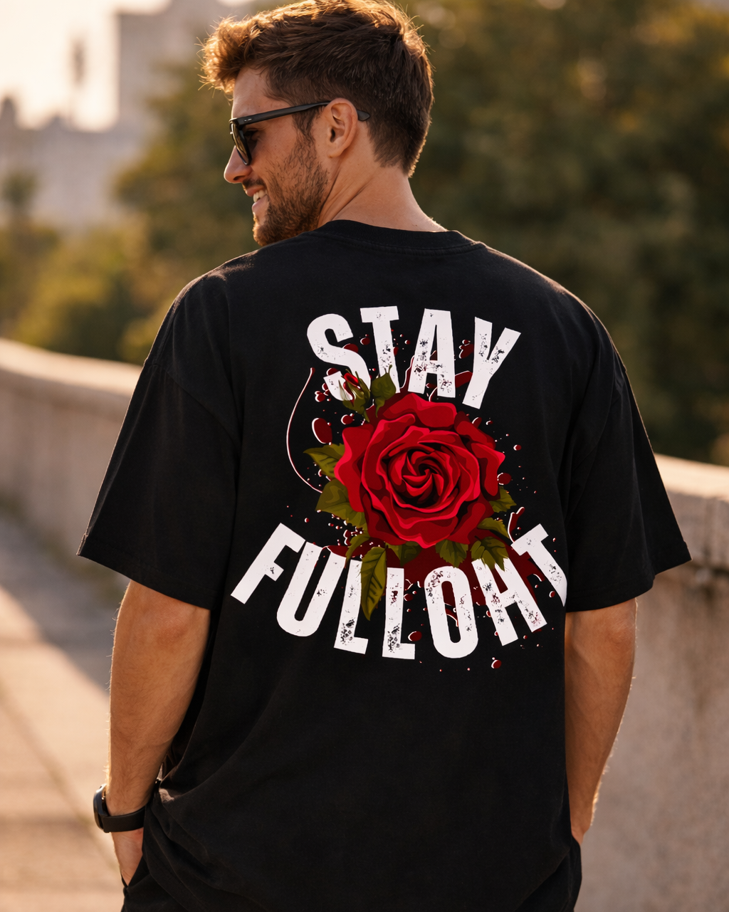 Man wearing a black t-shirt with a red rose graphic and 'Stay Fulloh' text on the back, standing outdoors.