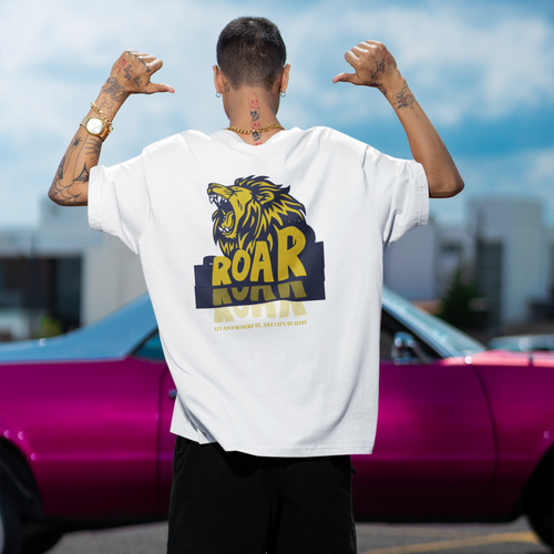 Person wearing a white t-shirt with a graphic design, standing in front of a pink car.