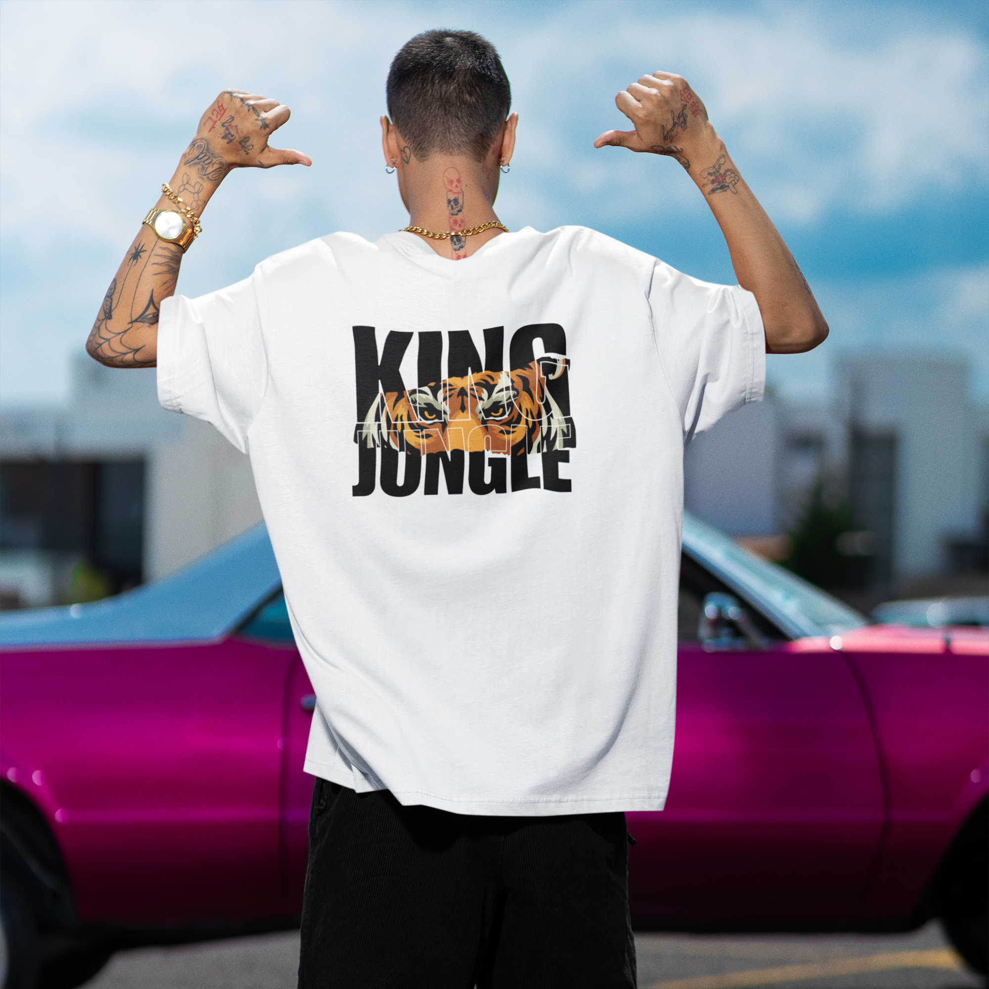 Person wearing a white t-shirt with 'King of the Jungle' graphic, standing in front of a pink car.