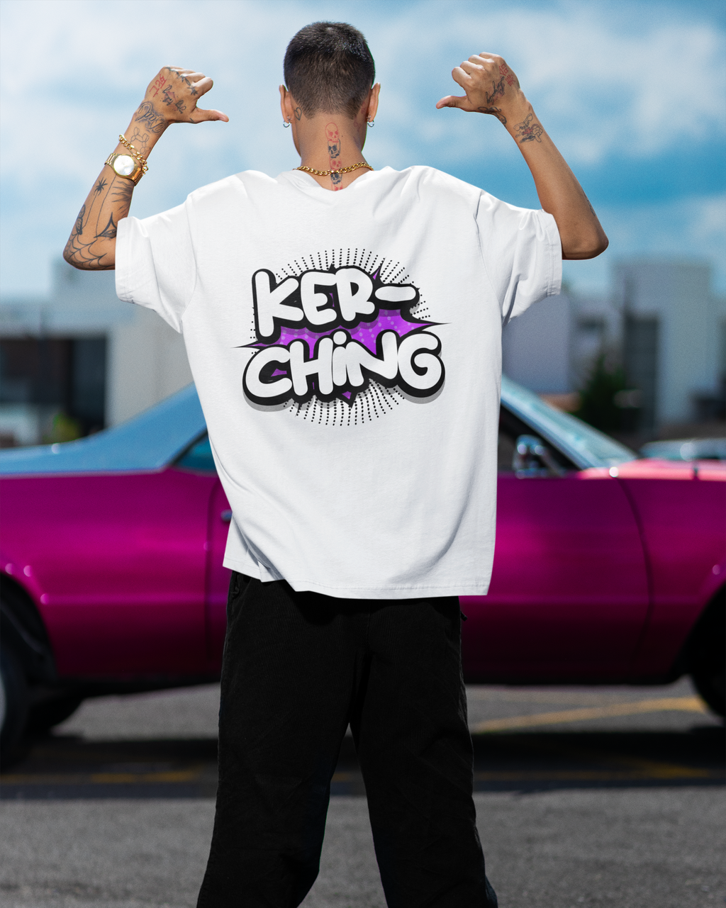 Person wearing a white t-shirt with 'KER-CHING' design, standing in front of a pink car.