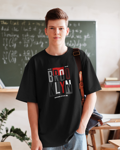 Person wearing a black t-shirt with 'Brooklyn' design in a classroom setting