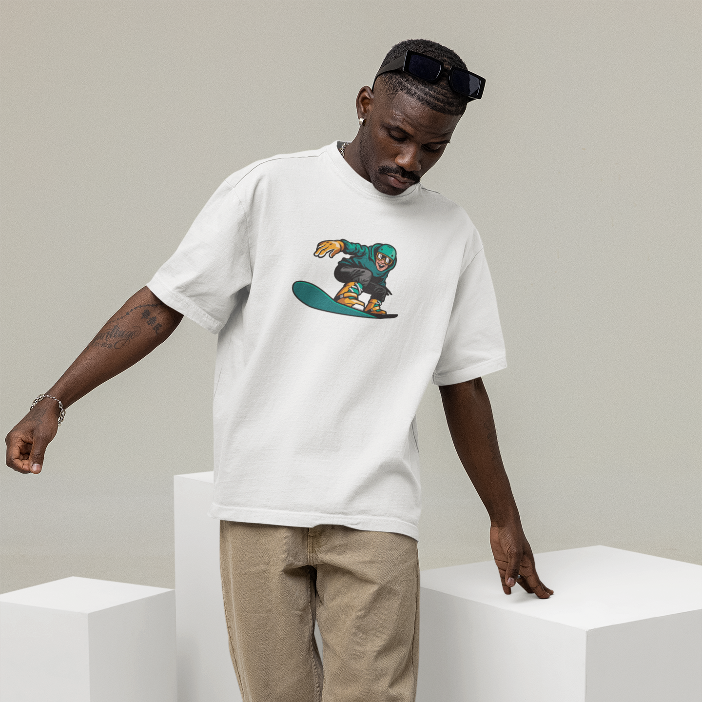 Man wearing a white t-shirt with a graphic design, standing on a white cube.