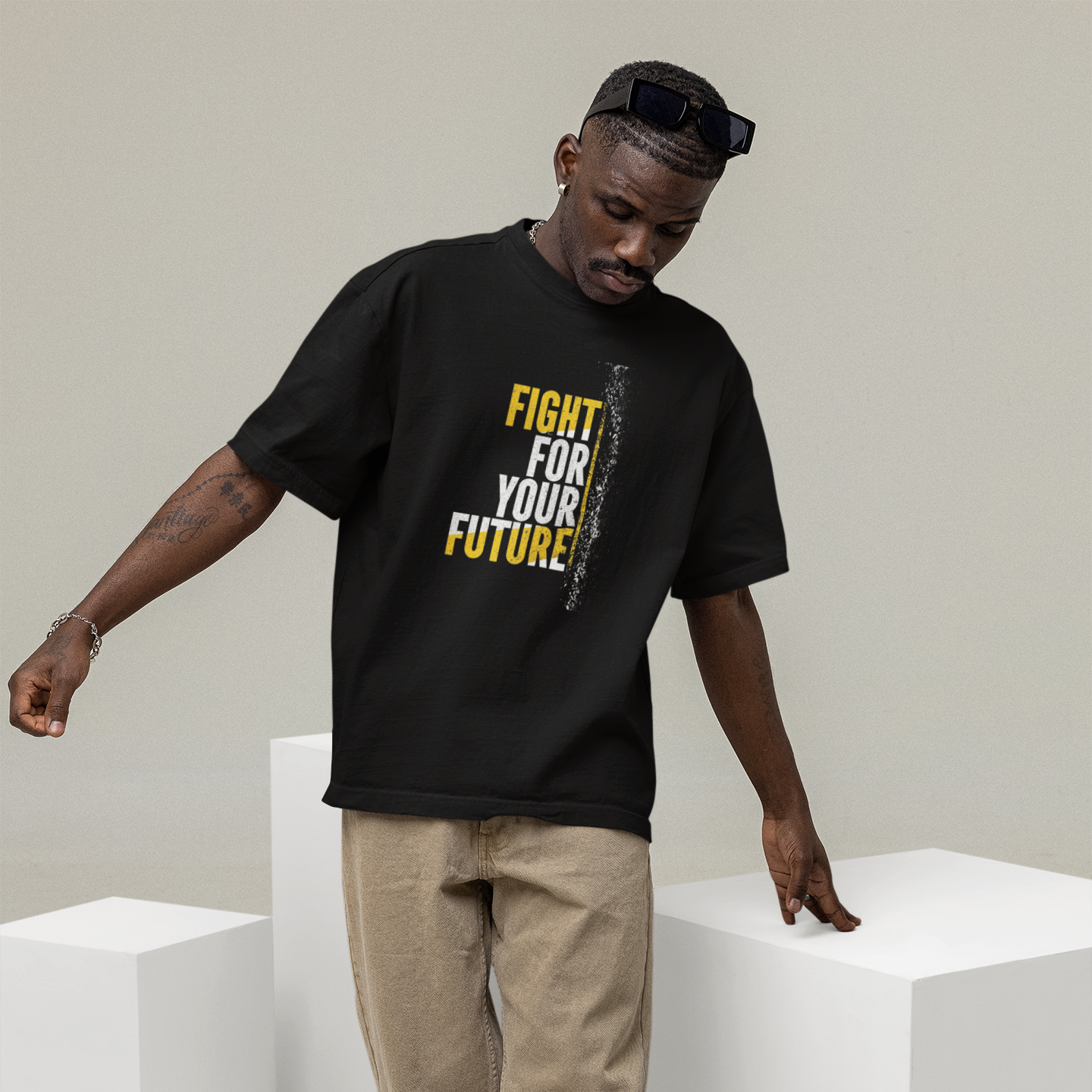 Man wearing a black t-shirt with 'Fight for Your Future' text, standing on white cubes against a plain background