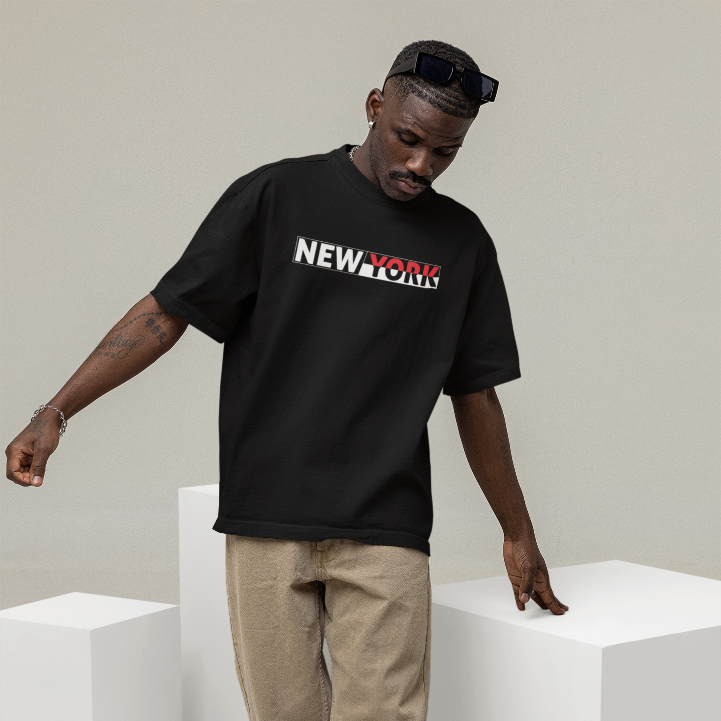 Man wearing a black 'New York' t-shirt standing between white cubes on a plain background
