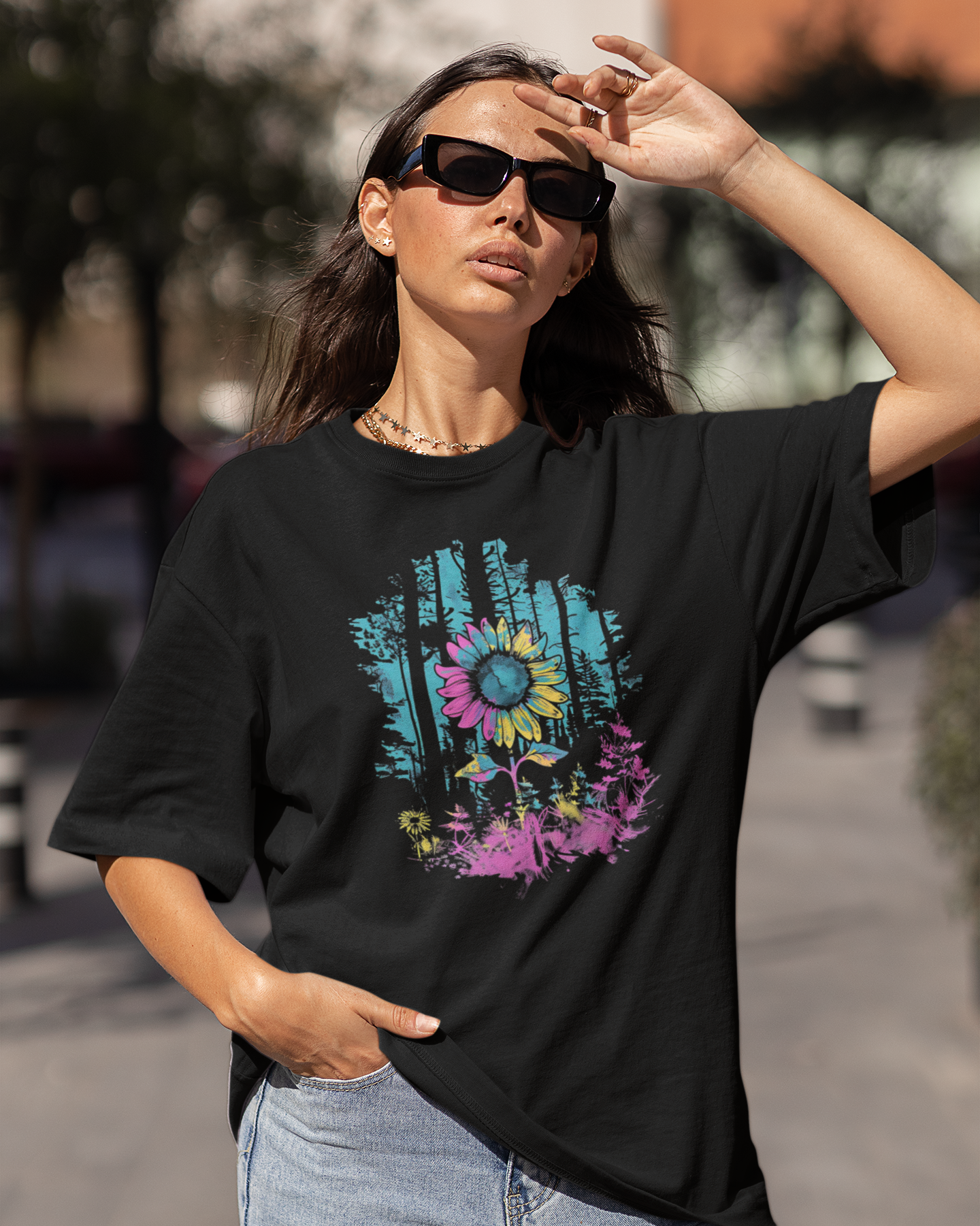 Woman wearing a black t-shirt with a colorful graphic design outdoors.